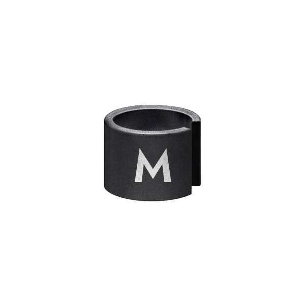A black cylindrical clamp with a white letter M on its surface. It has a slit down one side, creating an open ring shape. The background is plain white, highlighting the object.
