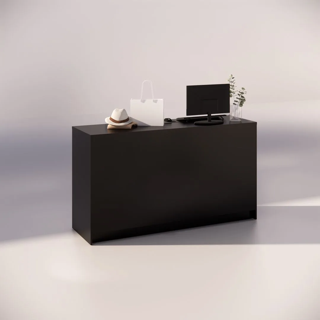 A minimalistic reception desk with a dark, sleek design. On the desk are a computer monitor, a white shopping bag, a hat, and a small plant. The setting is well-lit, creating a modern and professional atmosphere.